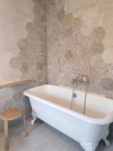 La salle de bains est pourvue d'une baignoire blanche et d'un tabouret. dans l'établissement Authentique Mas provençal avec son grand parc, à Orange