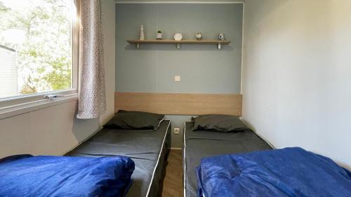 une chambre avec deux lits et une fenêtre dans l'établissement Mobilhome Trigano Samba 3 Bedrooms BA233 - La Palmyre Bonne Anse Plage, aux Mathes