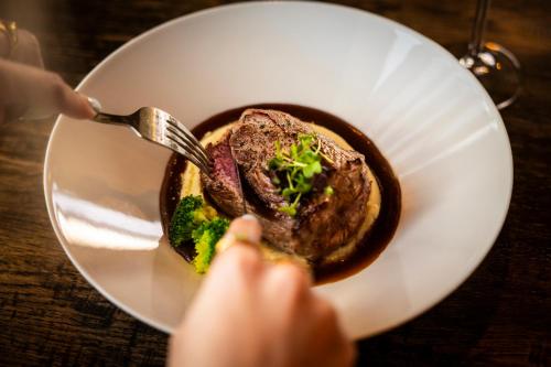 a person eating a plate of food with a steak at Hotel Restaurant Boschlust in Oudemirdum