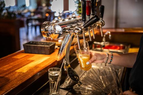 a person is holding a glass at a bar at Hotel Restaurant Boschlust in Oudemirdum