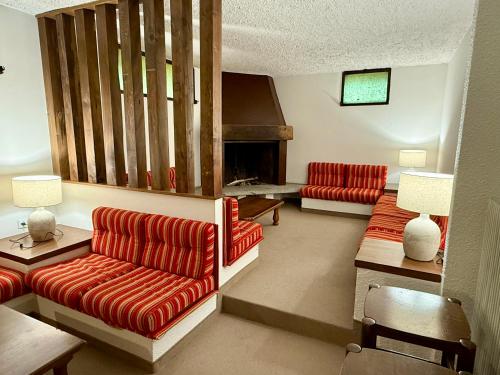 a living room with two red couches and a fireplace at Ursus Chalet in Carisolo