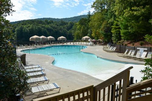 a large swimming pool with lounge chairs and trees at Lake and Golf Course Views Big Canoe Home with Deck! in Jasper