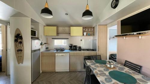 une cuisine avec une table et une salle à manger dans l'établissement Mobilhome Trigano Samba 3 Bedrooms BA233 - La Palmyre Bonne Anse Plage, aux Mathes