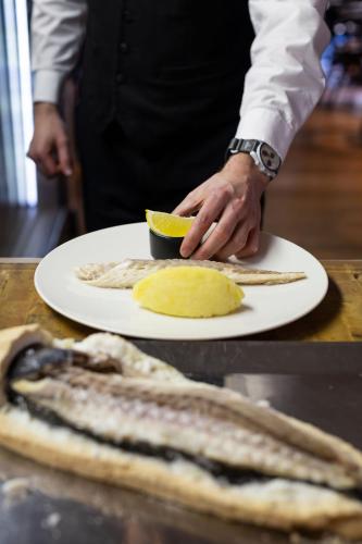 a chef holding a plate of fish and a lemon at La Cordée des Alpes SUP in Verbier