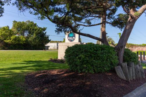 a sign for a house with a tree and a bush at Palm Suites in Atlantic Beach