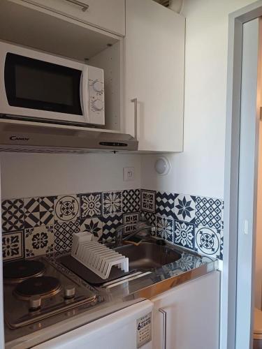 une cuisine avec un évier et un micro-ondes dans l'établissement Studio meublé 1 personne - Centre-ville Mail François Mitterrand, à Rennes