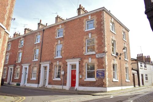 a brick building with a red door on a street at Grosvenor Place Guest House in Chester