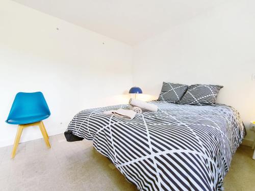 a bedroom with a black and white bed and a blue chair at Le Marcel Terrasse jardin in Auch
