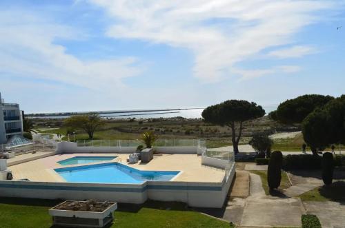 - une piscine dans une cour avec des arbres et un ciel dans l'établissement Appartement charmant à Le Grau-du-Roi avec piscine, au Grau-du-Roi