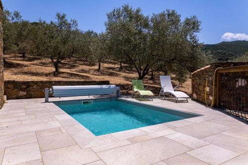 a swimming pool with a bench and two chairs at Domaine de Campu in Vallecalle