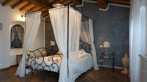 a bedroom with a canopy bed with white curtains at B&B CANNETO in Monteverdi Marittimo