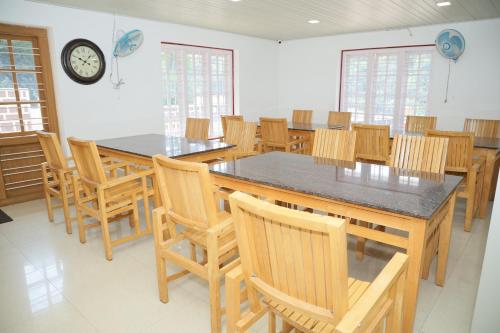 una sala da pranzo con un grande tavolo e sedie di Hotel Yajna Comforts a Madikeri