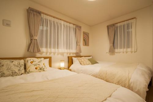 2 Betten in einem Schlafzimmer mit 2 Fenstern in der Unterkunft Magazine Home Tokyo Spacious 93 3BR Skytree7 minutesAsakusa12 minutes by train in Tokio