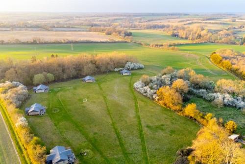 an aerial view of a green field with houses in it at Cuckoo - Sweffling Hall in Rendham