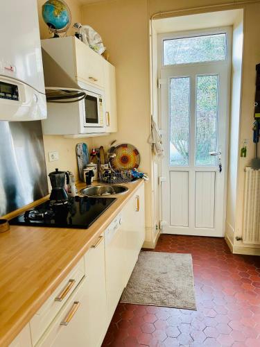 - une cuisine avec des placards blancs, un évier et une porte dans l'établissement Maison dans petit village du Morvan, à Vieux-Château