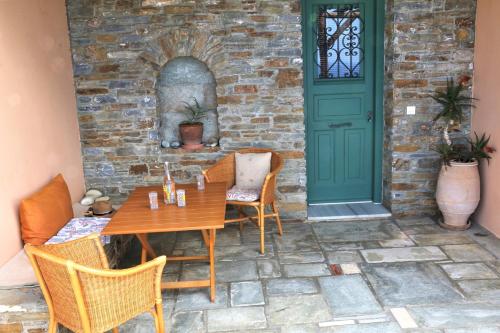 a table and chairs on a patio with a green door at Vereniki Andros guesthouse in Batsi