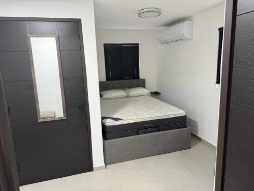 a small bedroom with a bed and a mirror at Casa Dushi Apartment in Oranjestad