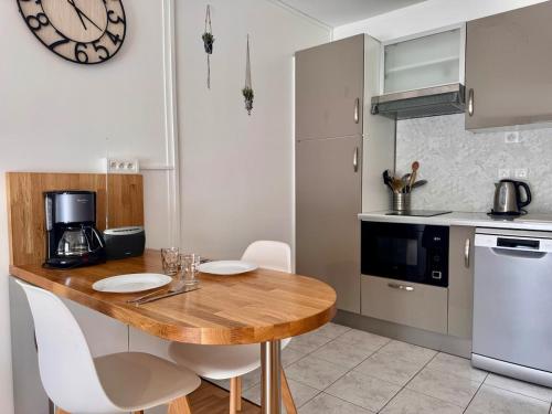 - une cuisine avec une table en bois et des chaises blanches dans l'établissement A 2 pas du port de plaisance, à Saint-Valery-sur-Somme