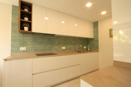 a kitchen with white cabinets and a sink at Beach House Castelldefels in Castelldefels