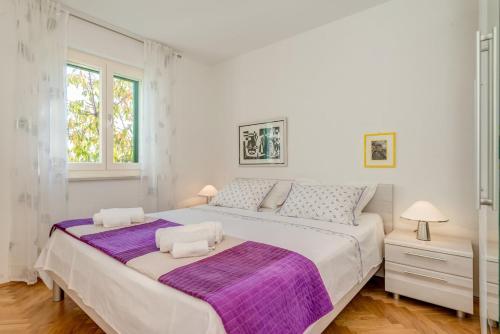 a white bedroom with a large bed and two windows at Villa Pax in Kastel Stafilic