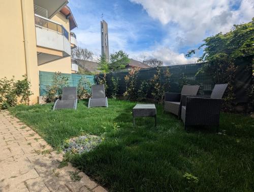 a yard with chairs and a table in the grass at Élégant et calme avec clim et jardin privé - Appartement Terracotta in Thonon-les-Bains