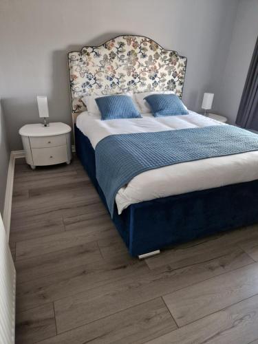 a bedroom with a bed with a blue blanket and blue pillows at The Cottage in Kirk of Shotts