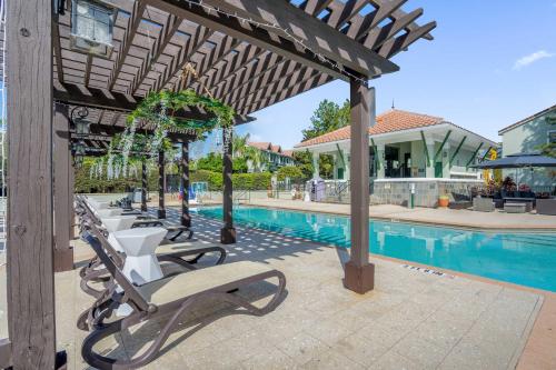 a row of chairs under a pergola next to a pool at Sunny Stay in FL - 4-Bedroom Townhome by Disney! in Orlando