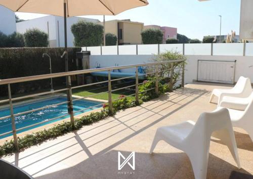 a balcony with a pool and chairs and an umbrella at MyStay - Villa Luísa in Vila do Conde