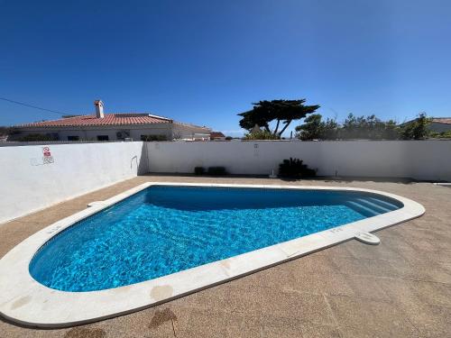 a large blue swimming pool sitting next to a white wall at Villa Coral in Cala en Porter