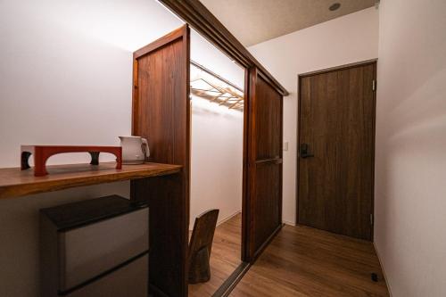 a hallway with a desk and a wooden door at 古民家ラグジュアリーホテル 金井西洋館 in Sado