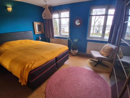 a bedroom with a bed and a chair and blue walls at House nearby Amsterdam in Almere