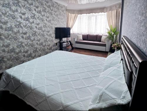 a bedroom with a white bed and a couch at 2х-ком Люкс Желтоксан 17а - 6й этаж лифт есть in Shymkent