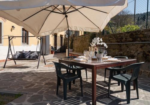 Una mesa con sillas y una sombrilla en un patio. en 30 Min from Florence Jacuzzi, Wi-Fi & Parking, en Scopeti