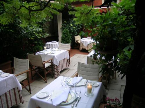 a patio with tables and chairs with white tablecloths at Villa Abbazia Relais & Chateaux in Follina