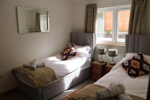 a bedroom with two beds and a mirror and a window at Luxury 2 bedroom property in quiet location close to SW Coastal Path in Paignton