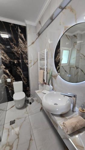 a bathroom with a sink and a toilet and a mirror at Catherine's Beachfront Apartment by Optimum Link in Paralia Katerinis
