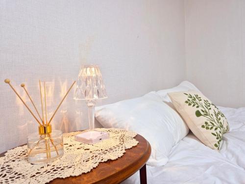 a table with a lamp on top of a bed at Private House Good Stay Samdeok in Daegu