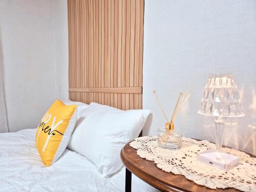 a bed with a table with a yellow pillow and a lamp at Private House Good Stay Samdeok in Daegu