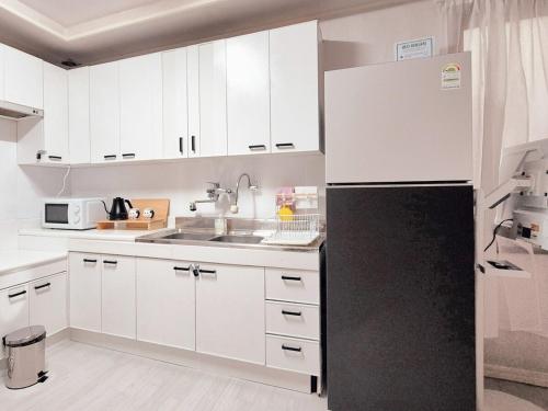 a kitchen with white cabinets and a black refrigerator at Private House Good Stay Samdeok in Daegu