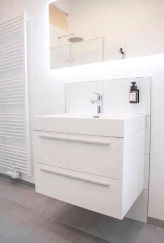 a white bathroom with a sink and a mirror at Helles Apartment im Herzen Mönchengladbachs in Mönchengladbach