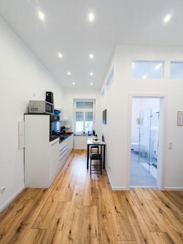 a kitchen with white walls and a wooden floor at Helles Apartment im Herzen Mönchengladbachs in Mönchengladbach