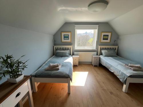 a bedroom with two beds and a window at Old Orchard in Saundersfoot