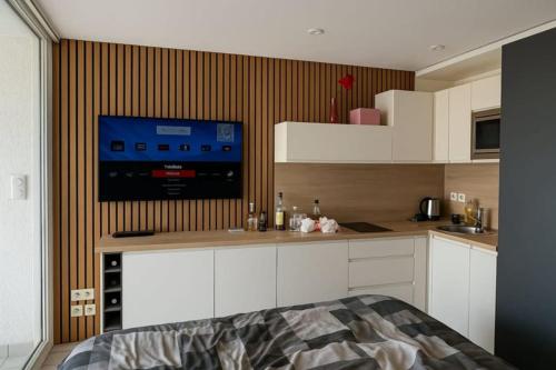 Il comprend une cuisine avec des placards blancs et une télévision murale. dans l'établissement Naturiste Cap d'Agde Port Vénus 104, au Cap d'Agde