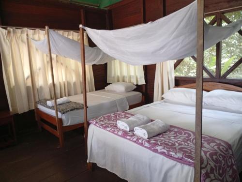 una camera con 2 letti e un letto a baldacchino di Lodge Parayso -Tambopata a Puerto Maldonado