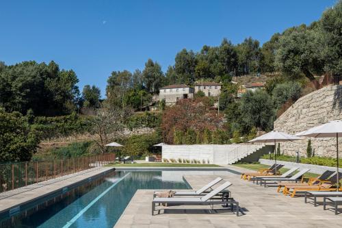 a swimming pool with lounge chairs and umbrellas at Quinta Leitão with 25m Pool & Gim by Sé Apartamentos in Vieira do Minho