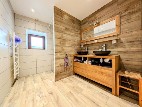 La salle de bains est pourvue de murs en bois et d'un lavabo. dans l'établissement La Grange de Jannine et Clémentine, à Saint-Germain-la-Chambotte