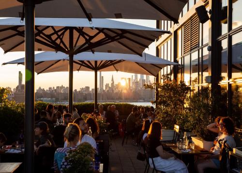 a group of people sitting at tables under umbrellas at Wythe Hotel in Brooklyn