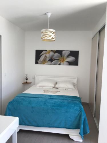 - une chambre blanche avec un lit et une couverture bleue dans l'établissement LA Marina, à Marcorignan