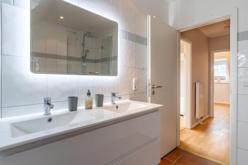 a white bathroom with a sink and a mirror at Diekhus SPO Diekhus 3 in Böhl