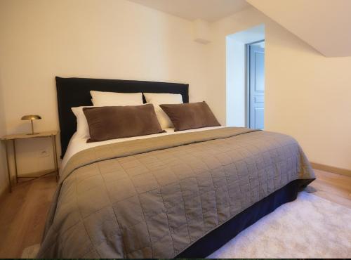 - une chambre avec un grand lit et des oreillers bruns dans l'établissement La Suite Des Légendes - Duplex climatisé - Centre historique, à Dole